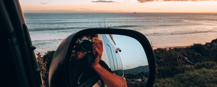 Man taking photo in car mirror