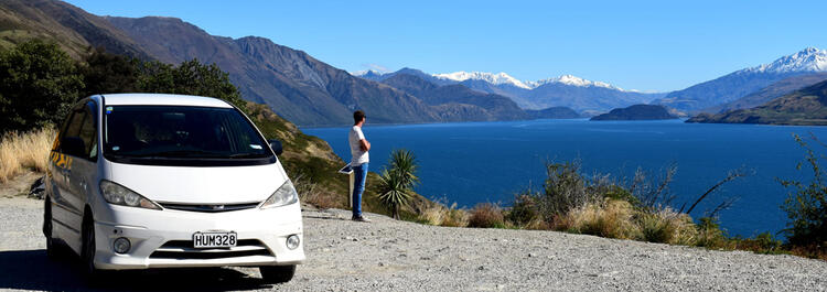 Mode Camper parked while person overlooks lake and mountains