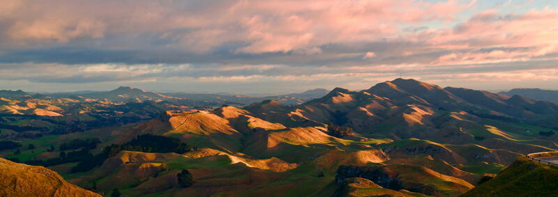 Rolling New Zealand hills under a cloudy sky at sunset