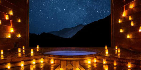 Hot pools at night with candles overlooking mountains