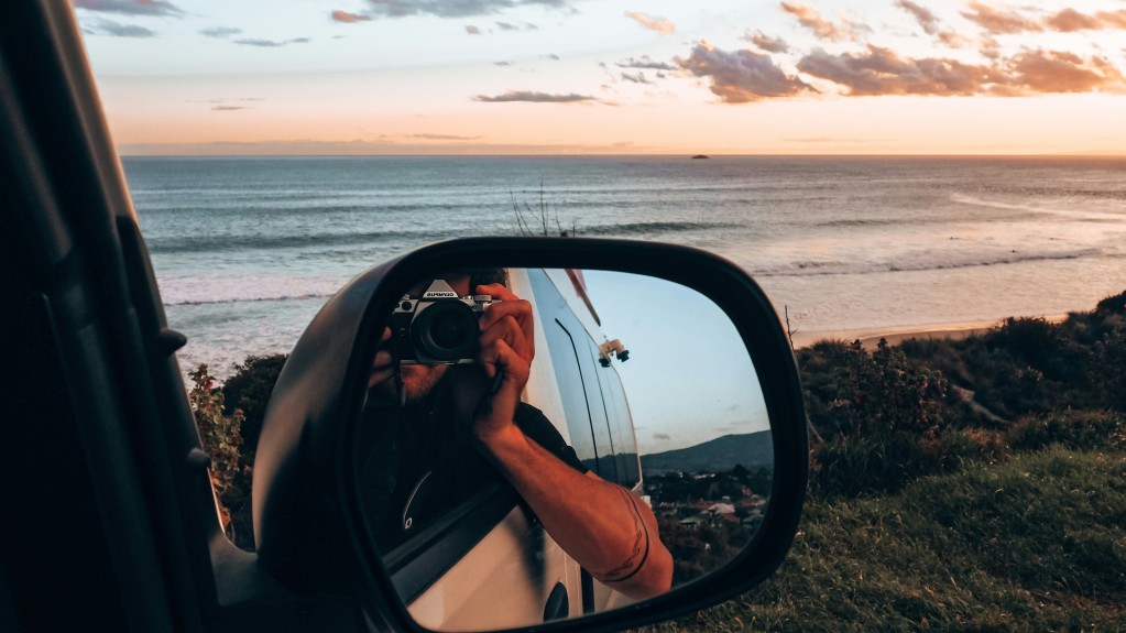 Man taking photo in car mirror