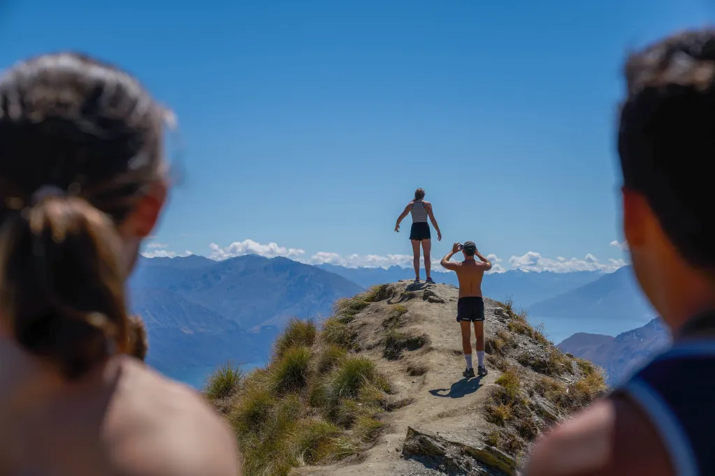Women and man looking at 2 people on mountain