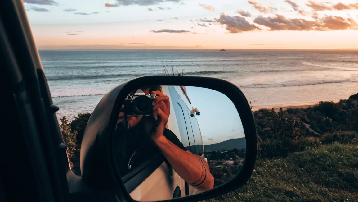 Man taking photo in car mirror